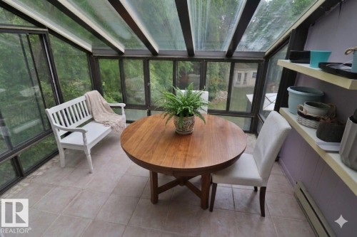 Sunroom featuring expansive glass panels, a full glass ceiling, light-toned tile flooring, and built-in shelving - 42 Alpaugh Crst, Leduc, AB 