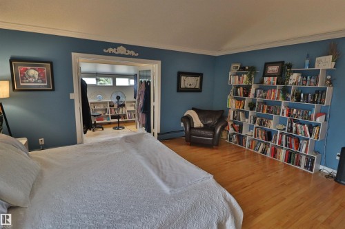 Hardwood flooring throughout featuring an open doorway to an additional room with built-in shelving, crown molding, and baseboard heating - 42 Alpaugh Crst, Leduc, AB 