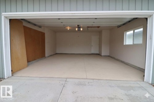 Spacious two-car garage with a light-colored concrete floor, white interior walls, and an overhead garage door opener - 42 Alpaugh Crst, Leduc, AB 