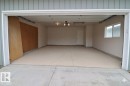 Spacious two-car garage with a light-colored concrete floor, white interior walls, and an overhead garage door opener - 42 Alpaugh Crst, Leduc, AB 