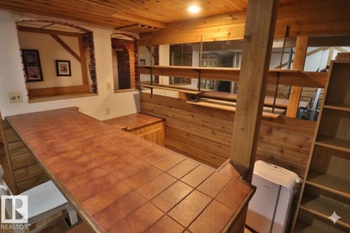 Tiled bar area featuring a wood-panel base and exposed ceiling beams - 42 Alpaugh Crst, Leduc, AB 
