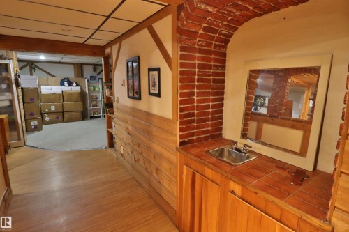 Brick archway featuring a built-in wet bar with a stainless steel sink, tiled countertop, and wood-finish cabinetry - 42 Alpaugh Crst, Leduc, AB 