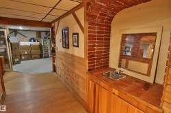 Brick archway featuring a built-in wet bar with a stainless steel sink, tiled countertop, and wood-finish cabinetry - 