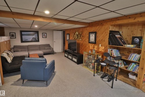 Recreational room featuring wood-paneled accent walls, integrated wood shelving, recessed lighting, carpet flooring, and a drop ceiling - 42 Alpaugh Crst, Leduc, AB 