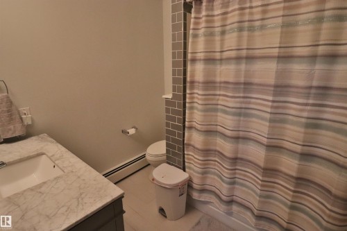 Bathroom featuring a vanity with an integrated sink and marble-finish countertop, toilet, and subway tile accent wall - 42 Alpaugh Crst, Leduc, AB 