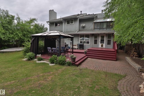 Expansive backyard featuring a red-stained deck with integrated steps, a paver stone patio, and a gazebo - 42 Alpaugh Crst, Leduc, AB 