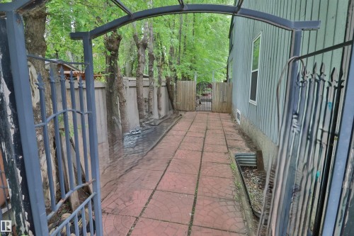 Exterior pathway featuring red-toned paver stones and a decorative metal archway - 42 Alpaugh Crst, Leduc, AB 