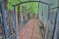 Exterior pathway featuring red-toned paver stones and a decorative metal archway - 