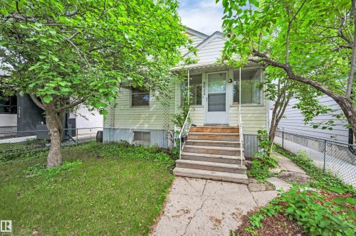Front exterior featuring a covered porch with white railing, wood steps, and a screen door - 9624 77 Avenue, Edmonton, AB 