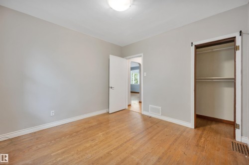 Room featuring wood-finish flooring, light grey painted walls, and white baseboards - 9624 77 Avenue, Edmonton, AB 