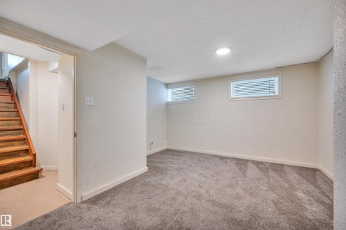 Lower-level room featuring plush gray carpeting, recessed lighting, and two windows with blinds - 9624 77 Avenue, Edmonton, AB 