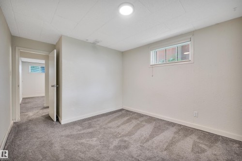Carpeted room featuring light-colored walls and a window with a white frame - 9624 77 Avenue, Edmonton, AB 
