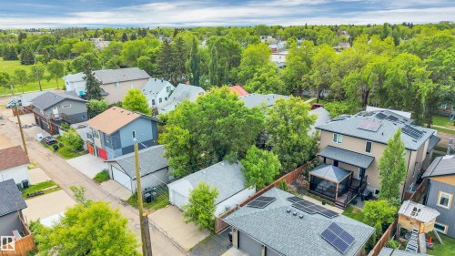 Residential property featuring a paved driveway, attached garage, and multiple solar panel installations - 9624 77 Avenue, Edmonton, AB 