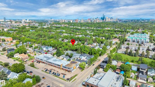 Aerial perspective showcasing extensive tree canopy, mixed residential and commercial structures, and a distant city skyline - 9624 77 Avenue, Edmonton, AB 