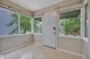 Enclosed porch featuring multiple large windows, a white paneled entry door with smart lock, light-toned walls, and neutral-colored tile flooring - 9624 77 Avenue, Edmonton, AB 