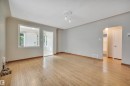 Spacious interior room featuring wood-finish flooring, light gray wall paint, and white trim - 9624 77 Avenue, Edmonton, AB 