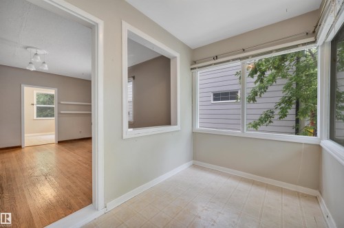 Bright interior space featuring a window wall, neutral wall paint, and white trim - 9624 77 Avenue, Edmonton, AB 
