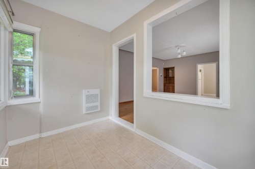 Room featuring light-toned walls, patterned tile flooring, and multiple windows - 9624 77 Avenue, Edmonton, AB 