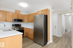 Kitchen featuring light wood cabinetry, white countertops, stainless steel appliances, a white subway tile backsplash, and light wood-finish flooring - 
