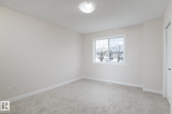 Spacious room featuring neutral paint, light gray carpeting, and a white window frame - 