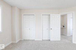 Carpeted interior room featuring two sets of paneled bi-fold closet doors, a white trim window, and neutral wall paint - 