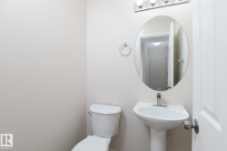 Powder room featuring a pedestal sink with a single-handle faucet, oval mirror, and a three-light vanity fixture - 