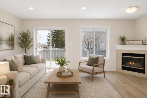 Living area featuring a tiled fireplace with a classic white mantelpiece, light wood-finish flooring, and recessed ceiling lighting - 55 14603 Miller Boulevard, Edmonton, AB 