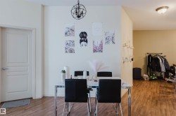 Open-concept interior featuring wood-finish flooring, a contemporary chandelier, a panel door, and light-toned walls - 