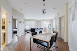 Open-concept living area with wood-finish flooring, a contemporary chandelier, and large windows with privacy blinds - 