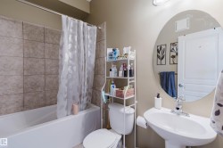 Bathroom with a pedestal sink, a circular wall-mounted mirror, and a toilet - 