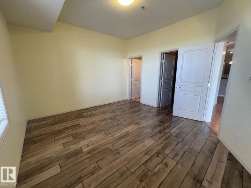 Spacious room featuring wood-finish plank flooring and light-toned walls - 323 4831 104A Street, Edmonton, AB 