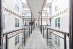 Covered outdoor walkway featuring a textured concrete surface and contemporary glass and metal railings - 