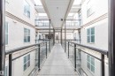 Covered outdoor walkway featuring a textured concrete surface and contemporary glass and metal railings - 323 4831 104A Street, Edmonton, AB 