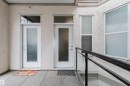 Exterior entry featuring two white doors with frosted glass panels, transom windows, and textured stucco finish - 323 4831 104A Street, Edmonton, AB 