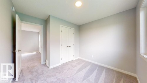 Spacious interior featuring light gray carpeting, a built-in closet with double doors, and a window providing natural illumination - 3918 3A Avenue, Edmonton, AB 