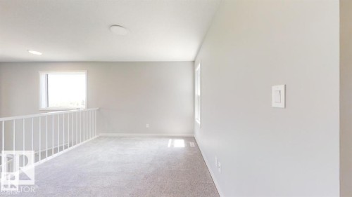 Carpeted loft area featuring a white railing, two recessed ceiling lights, and two windows - 3918 3A Avenue, Edmonton, AB 