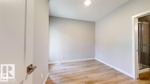 Interior room featuring wood-finish flooring, light gray wall paint, and white baseboards - 3918 3A Avenue, Edmonton, AB 