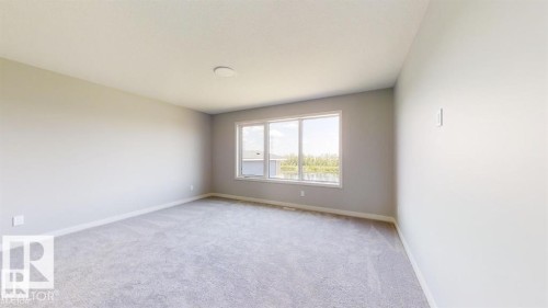 Spacious interior room featuring light gray carpeting, white baseboards, and a multi-pane window with white trim - 3918 3A Avenue, Edmonton, AB 