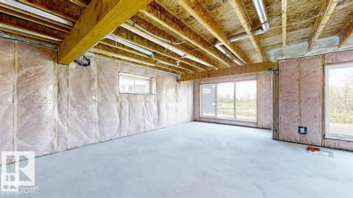 Unfinished interior space featuring a concrete floor, exposed wooden ceiling beams, and insulated walls - 3918 3A Avenue, Edmonton, AB 