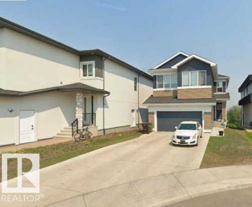 Contemporary two-story residence featuring a dark blue facade with tan horizontal siding and a two-car garage - 3918 3A Avenue, Edmonton, AB 