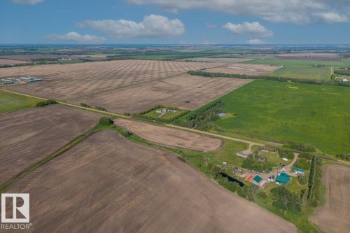 Expansive agricultural property featuring multiple cultivated fields, a mix of brown and green crops, and a central road access point - 0 0, Rural Sturgeon County, AB 
