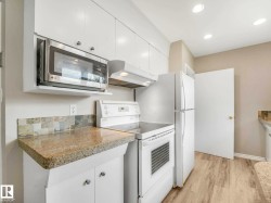 Kitchen featuring white cabinetry, light-toned countertops with a tiled backsplash, and recessed lighting - 