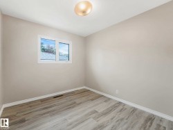 Light-filled room featuring wood-finish flooring, neutral wall tones, white trim, a single window, and a ceiling-mounted light fixture - 