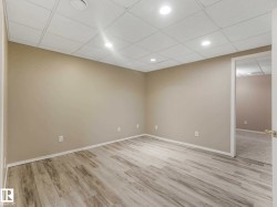 Versatile room featuring light wood-finish flooring, neutral wall paint, and a white drop ceiling with recessed lighting - 