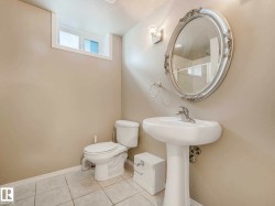 Bathroom featuring a pedestal sink, white toilet, and tile flooring - 