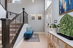 Foyer featuring light wood-finish flooring, a grand staircase with dark wood newel posts and railings, and a white entry door - 