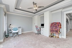 Recessed lighting illuminates a coffered ceiling with a decorative central panel and a ceiling fan - 