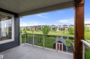Covered balcony featuring a wood-finish support beam, glass railing, overlooking pond - 164 Durrand Bend, Fort Saskatchewan, AB 
