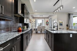 Contemporary kitchen featuring dark wood cabinetry, a subway tile backsplash, and light-toned flooring - 