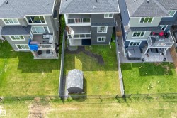 Expansive backyard featuring a manicured lawn, a gravel path, and a permanent storage shed - 